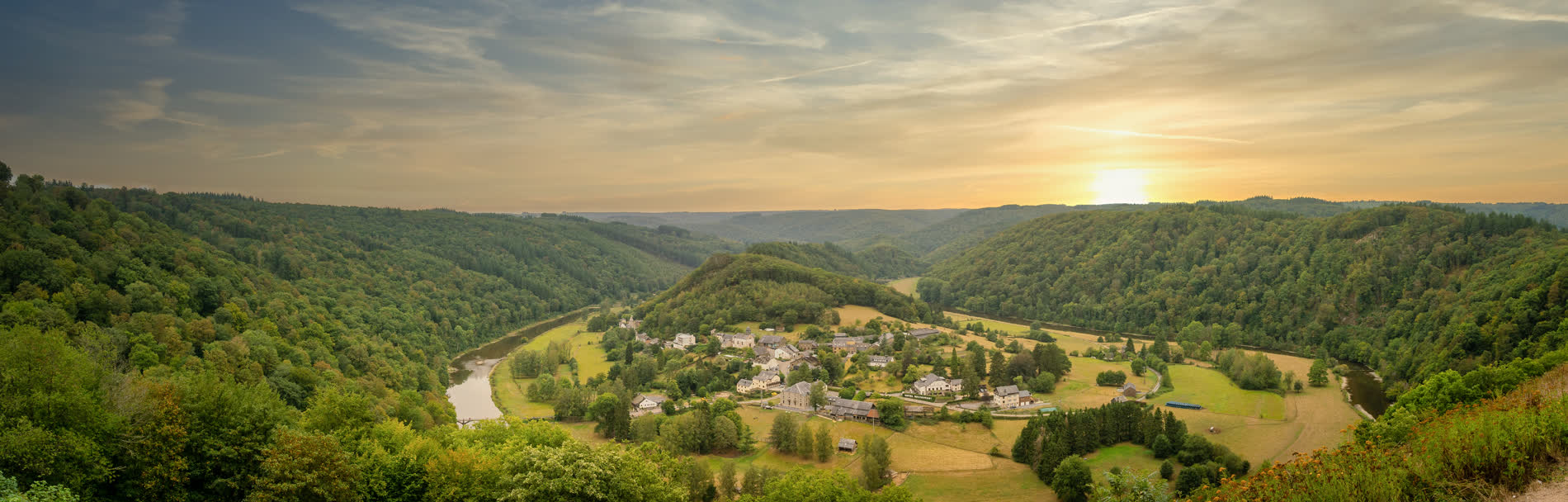 Panorama eines Flusses in einer Hufeisenschleife um ein Dorf, ringsum bewaldete Hänge im Abendlicht Panorama eines Flusses in einer Hufeisenschleife um ein Dorf, ringsum bewaldete Hänge im Abendlicht